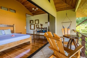 A bedroom with a bed, wooden floor, and a view of the outdoors. - Drake Bay Getaway Resort By Sandglass (Drake Bay)