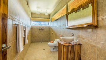 Un baño con tocador de madera, lavamanos y retrete.