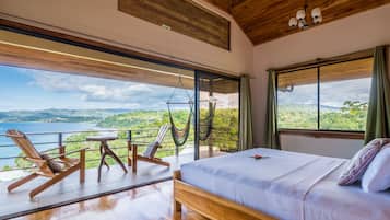 Un dormitorio con una cama grande, muebles de madera y un balcón con vistas al paisaje.