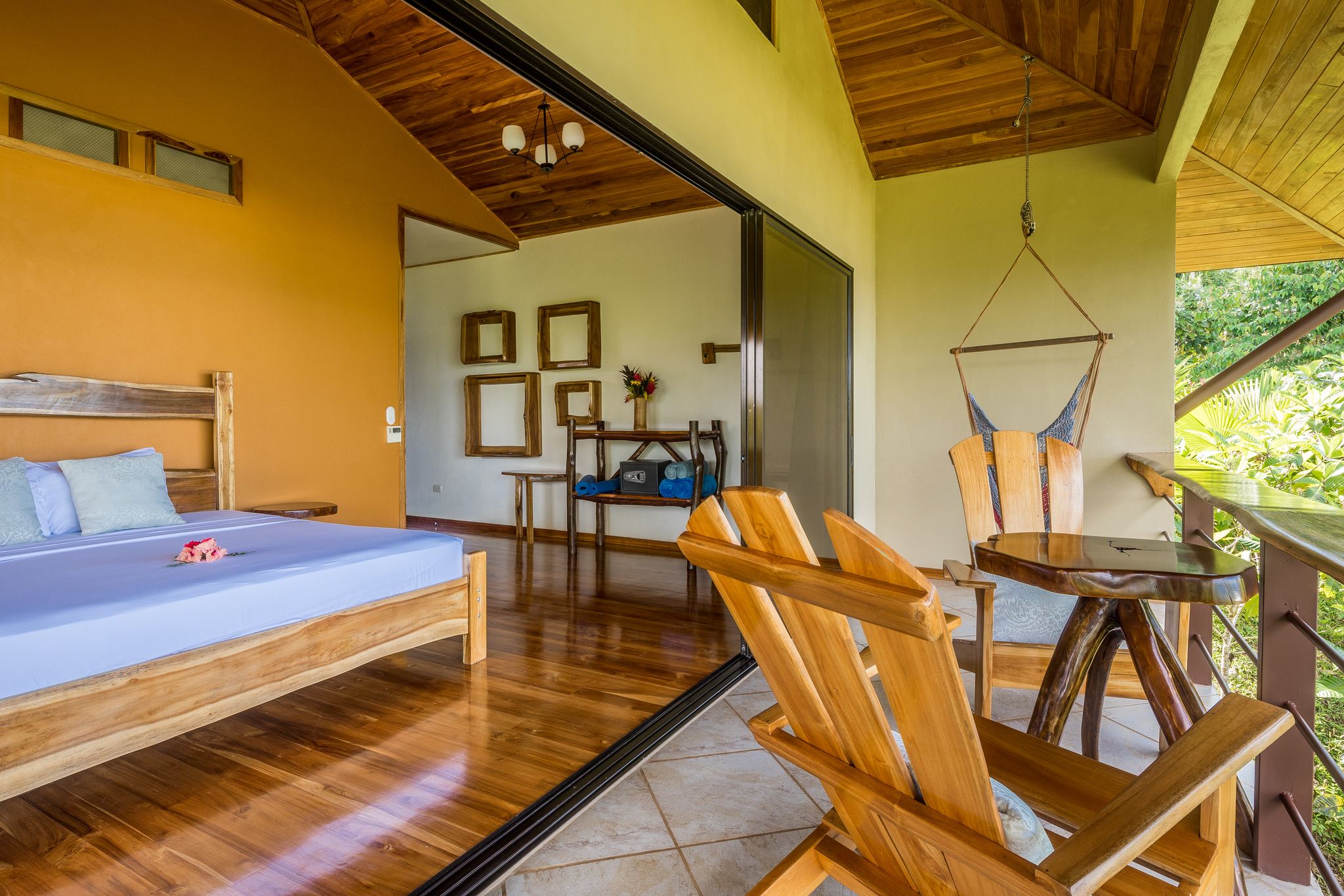 A bedroom with a bed, wooden floor, and a view of the outdoors.