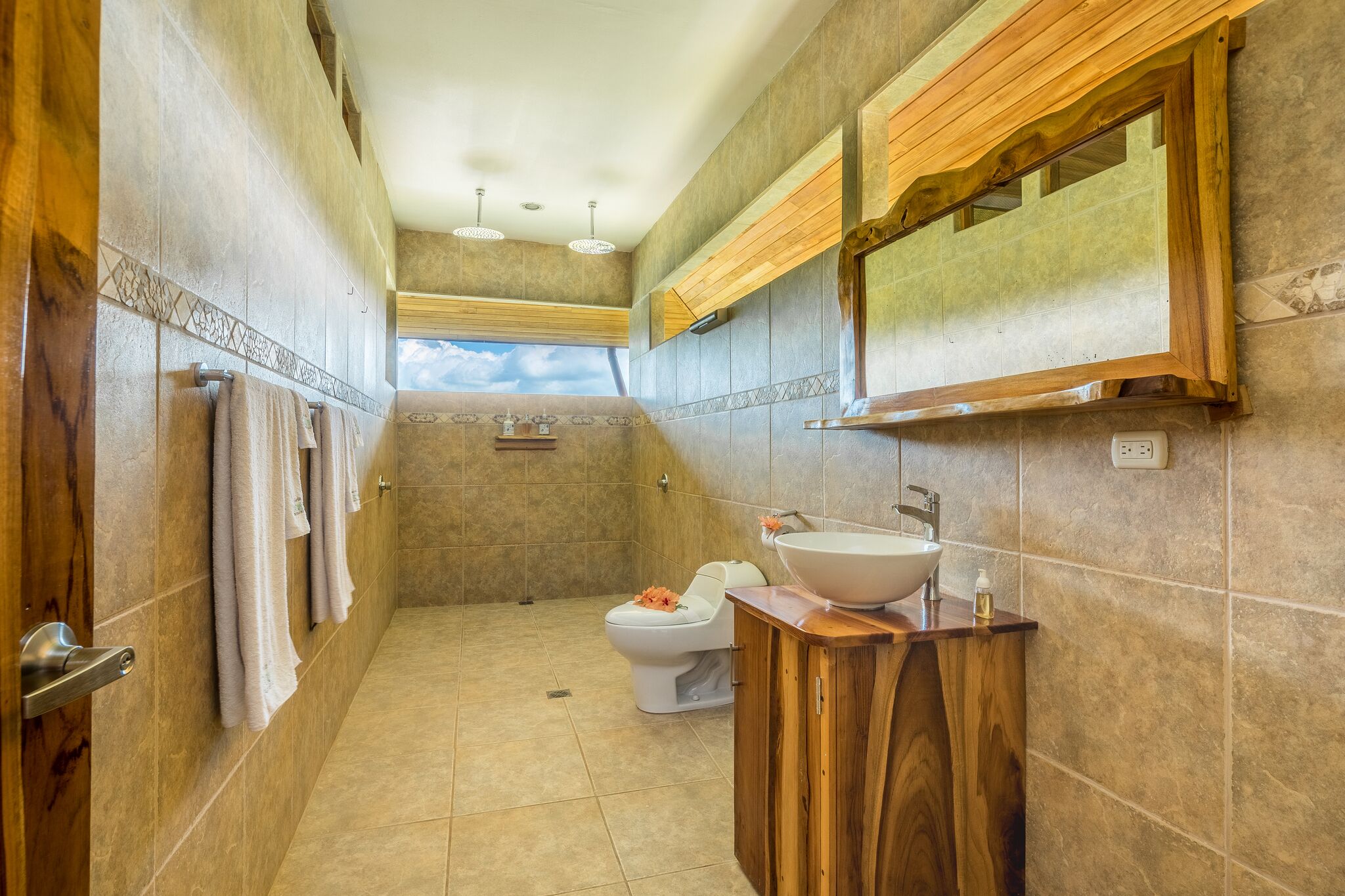 A bathroom with a wooden vanity, a sink, and a toilet.