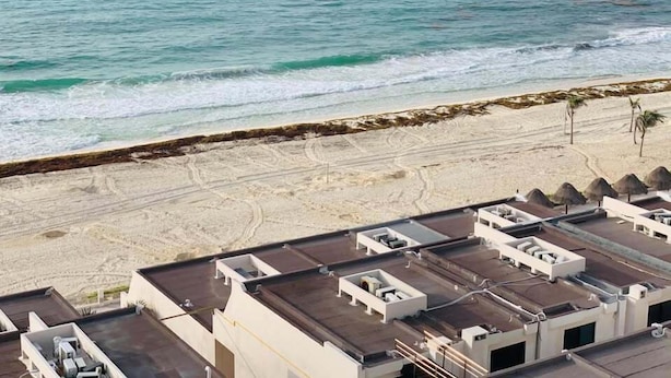 A beachside hotel with multiple rooftop terraces, a sandy beach, and a view of the ocean. - Casa Laurel (Cancun)