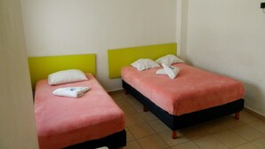 A small hotel room with two single beds, each with a pillow and a folded towel. - Casa Laurel (Cancun)