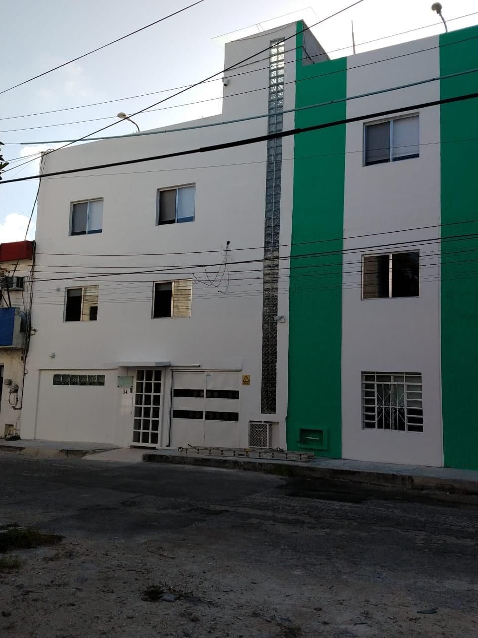 Un edificio de varios pisos con fachada blanca y una franja vertical verde.