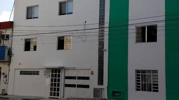 Un edificio de varios pisos con fachada blanca y una franja vertical verde.