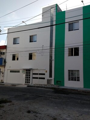A multi-story building with a white facade and a green vertical stripe. - Casa Laurel (Cancun)