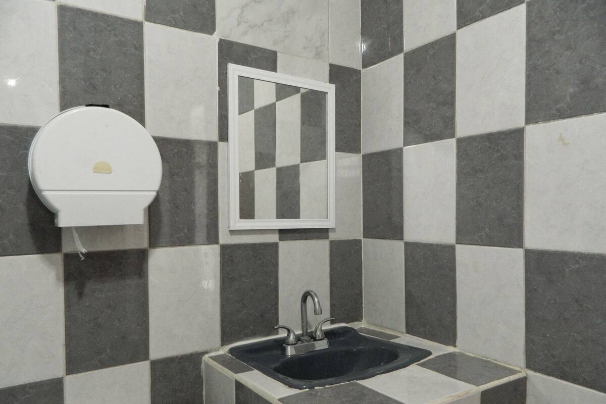 A bathroom with a checkered tile wall, a white toilet, a sink with a faucet, and a mirror.