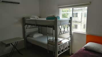 A bunk bed room with a window, a small table, and a purple bedspread.