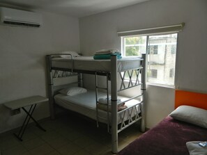 Una camera con letto a castello, una finestra, un piccolo tavolo e una coperta viola.