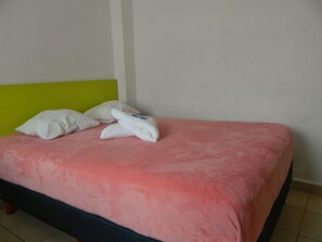 A bed with a pink bedspread, two white pillows, and a folded white towel. - Casa Laurel (Cancun)
