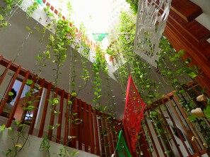 A room with a sloped ceiling, wooden beams, and hanging plants. - Casa Laurel (Cancun)