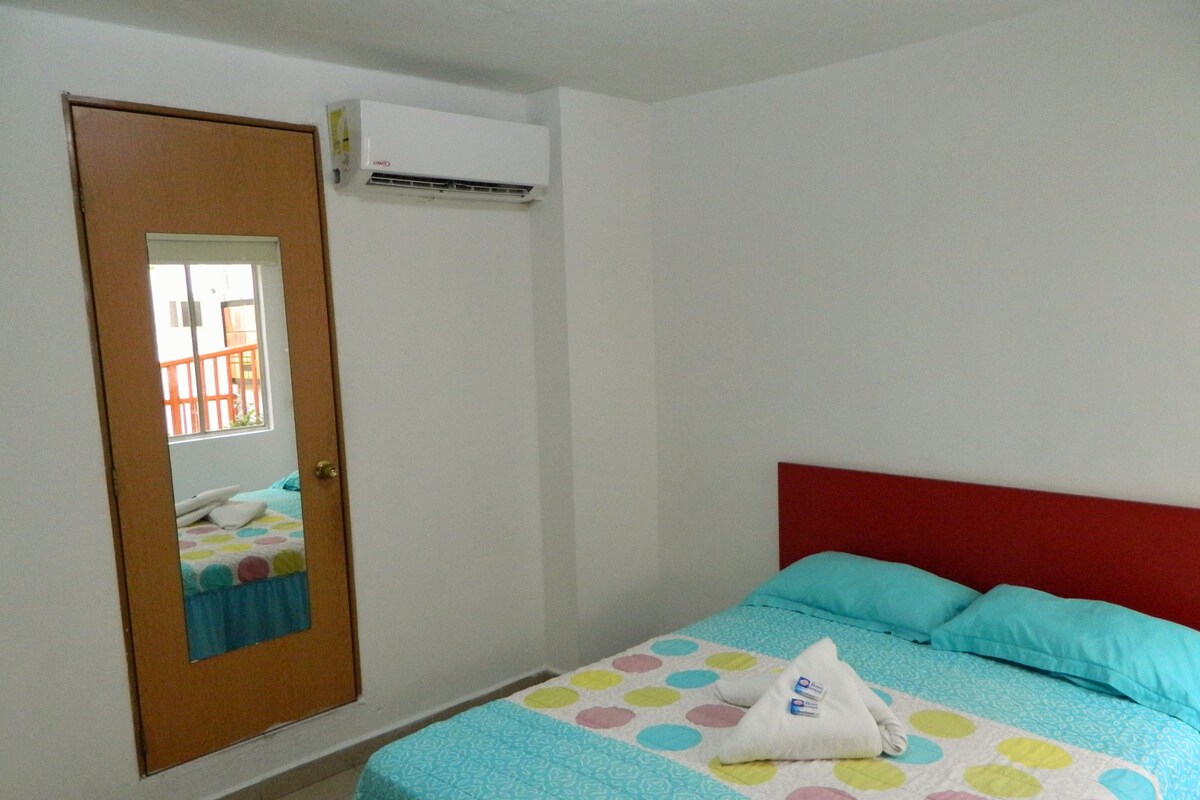 A bedroom with a bed, a door, and an air conditioning unit.