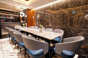 Un comedor moderno con una mesa de mármol, sillas estampadas y una lámpara decorativa.