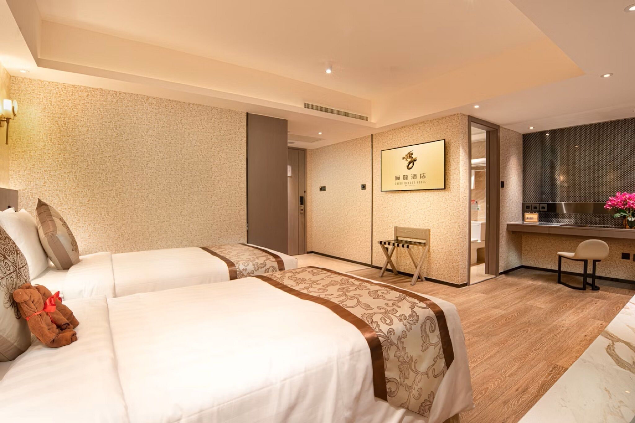 A hotel room with two beds, a small seating area, a kitchenette, and a bathroom.