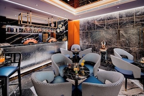 Un espace bar avec un mur en marbre, un comptoir bien garni de diffĂ©rentes bouteilles et des siĂšges disposĂ©s autour dâune table ronde.