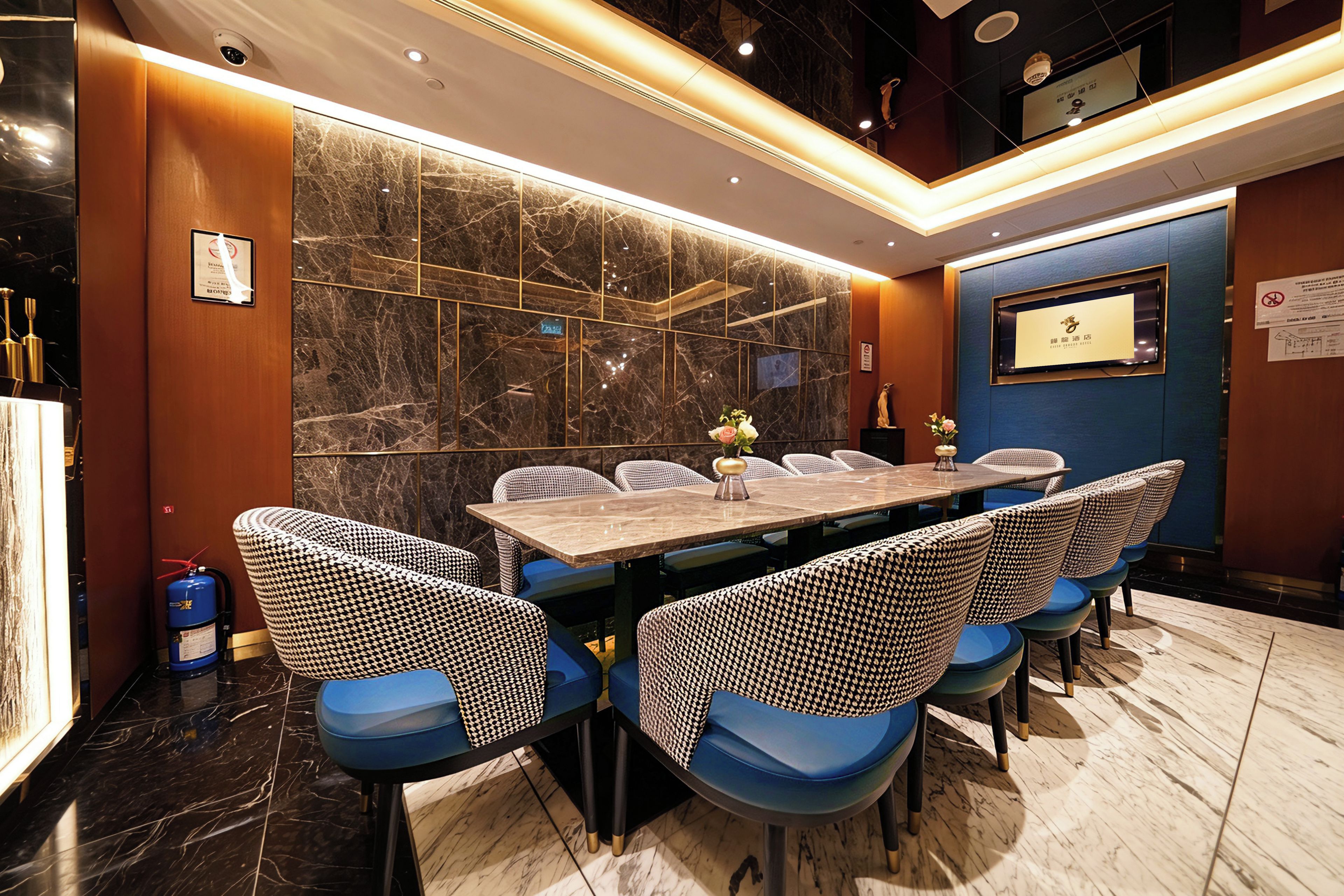 A conference room with a marble wall, a long table, and blue chairs.