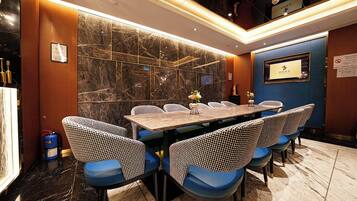 A conference room with a marble wall, a long table, and blue chairs.