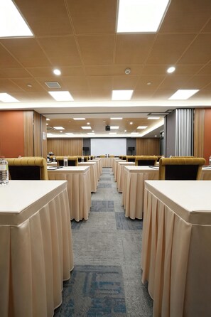A conference room with multiple tables and chairs, a carpeted floor, and a projector screen at the front. - China Dragon Hotel (Macau)