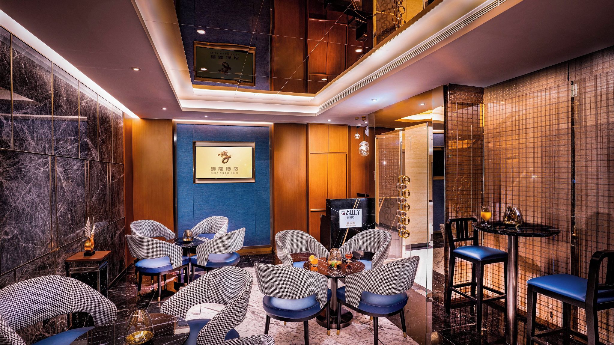 A hotel lobby with checkered chairs, a reception desk, and a marble wall.