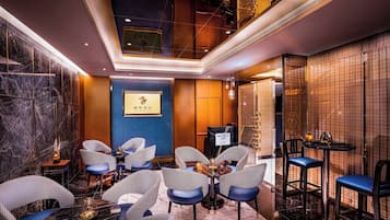 A hotel lobby with checkered chairs, a reception desk, and a marble wall.