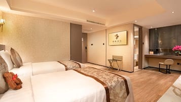 Habitación de hotel con dos camas, una zona de estar pequeña, kitchenette y baño.