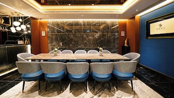 Una sala conferenze con pavimento in marmo, un lungo tavolo e sei sedie con cuscini blu.