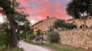A rural road leading to a stone-walled building with a balcony, surrounded by trees and vegetation. - Lovely home in Casciana Terme (Casciana Terme)