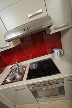 A compact kitchen with a stainless steel stove, a sink, and a kettle. - Noverian Scenic Crete 5 Hilltop Villa Resort &spa (Hersonissos)