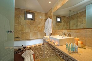 A bathroom with a bathtub, a large mirror, a sink, and candles. - Noverian Scenic Crete 5 Hilltop Villa Resort &spa (Hersonissos)