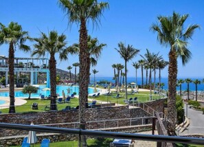 A resort with a pool, palm trees, and a view of the ocean. - Noverian Scenic Crete 5 Hilltop Villa Resort &spa (Hersonissos)