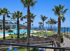 Un resort con piscina, palmeras y vista al océano.