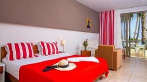 Une chambre d’hôtel avec un lit, une chaise, une table et une vue sur des palmiers.