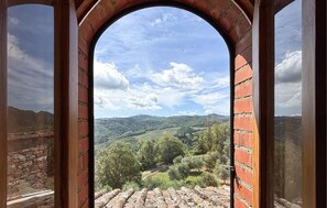 A view through a brick archway with a rural landscape, including hills and trees.