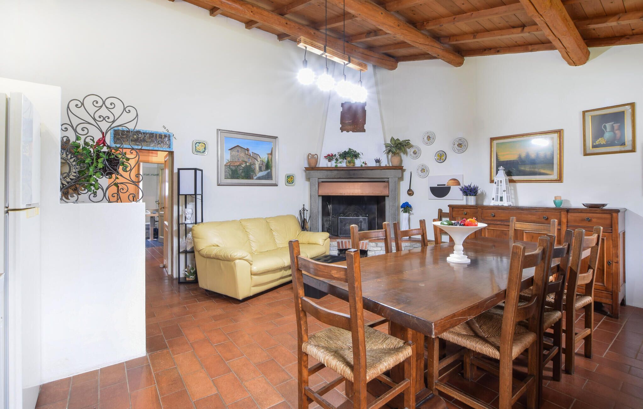 A dining area with a wooden table and chairs, a fireplace, and a yellow sofa.