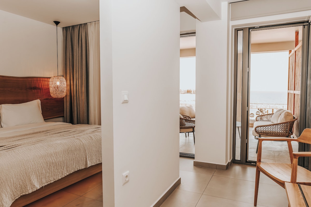 Una habitación de hotel con una cama, una silla de mimbre y vistas al balcón.