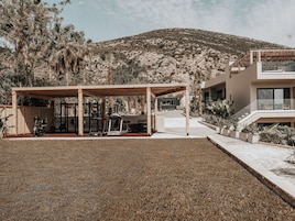 A modern outdoor gym area with exercise equipment, a covered seating area, and a view of a mountainous landscape.