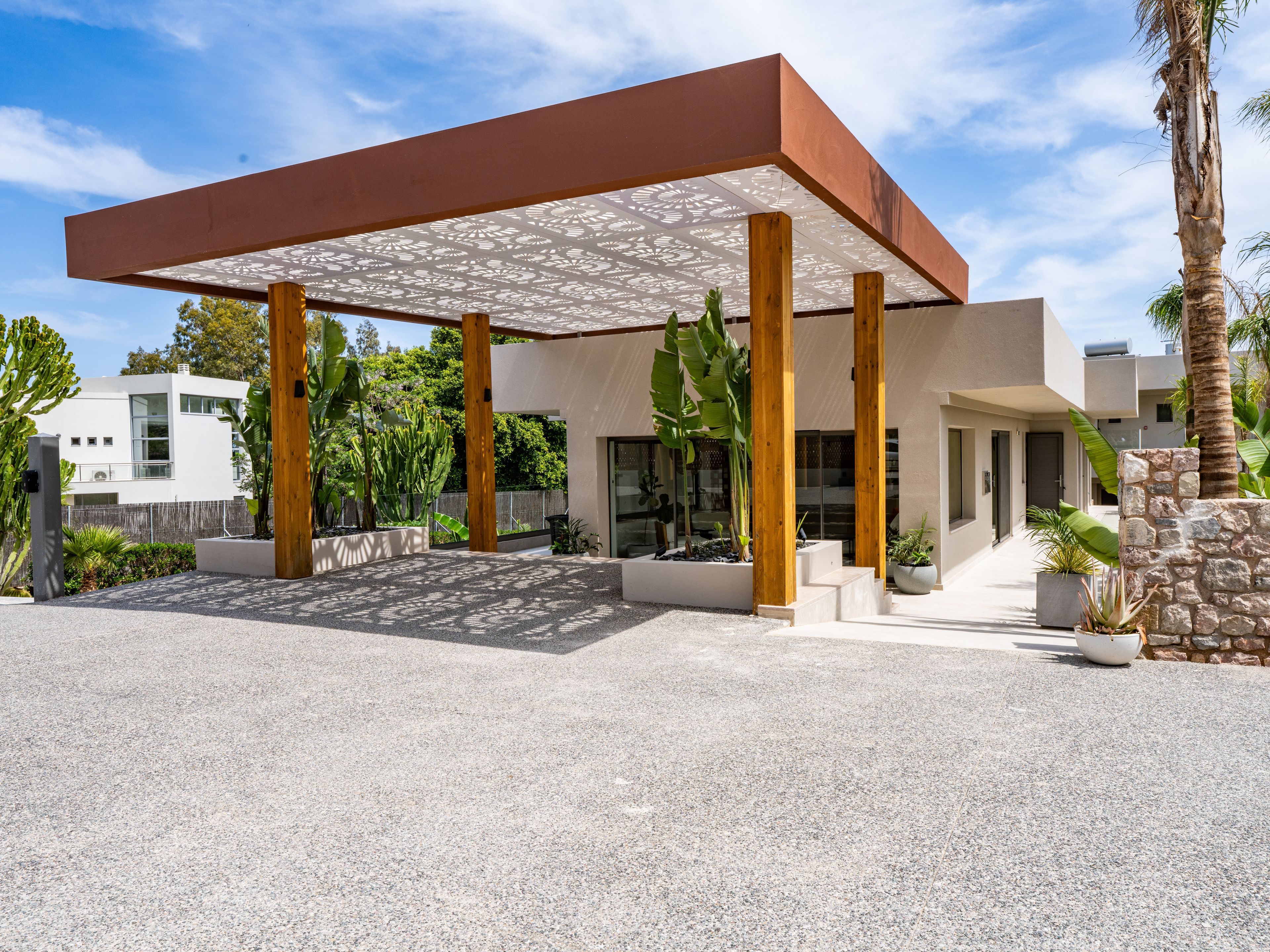 A modern building with a covered patio area, large windows, and a stone wall.