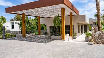 A modern building with a covered patio area, large windows, and a stone wall.