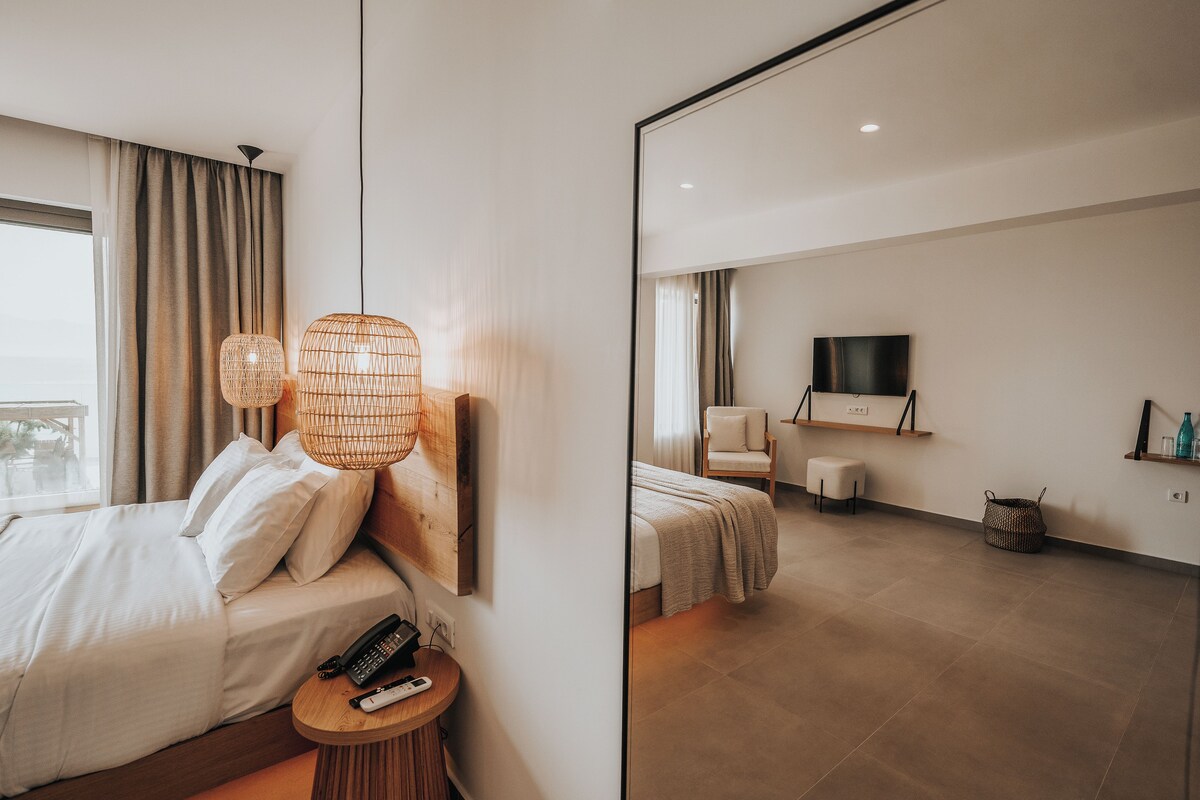 A hotel room with a bed, bedside table, lamp, and a TV on the wall.
