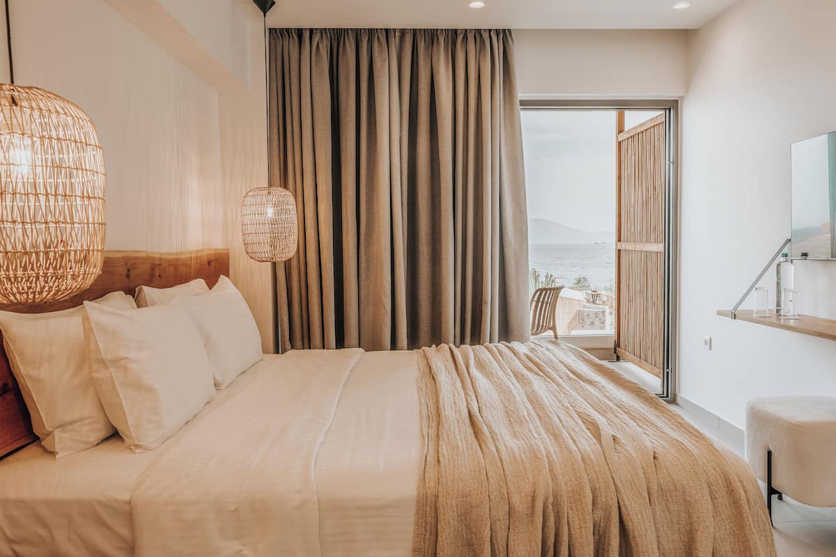 A bedroom with a large bed, a view of the sea, and a balcony.
