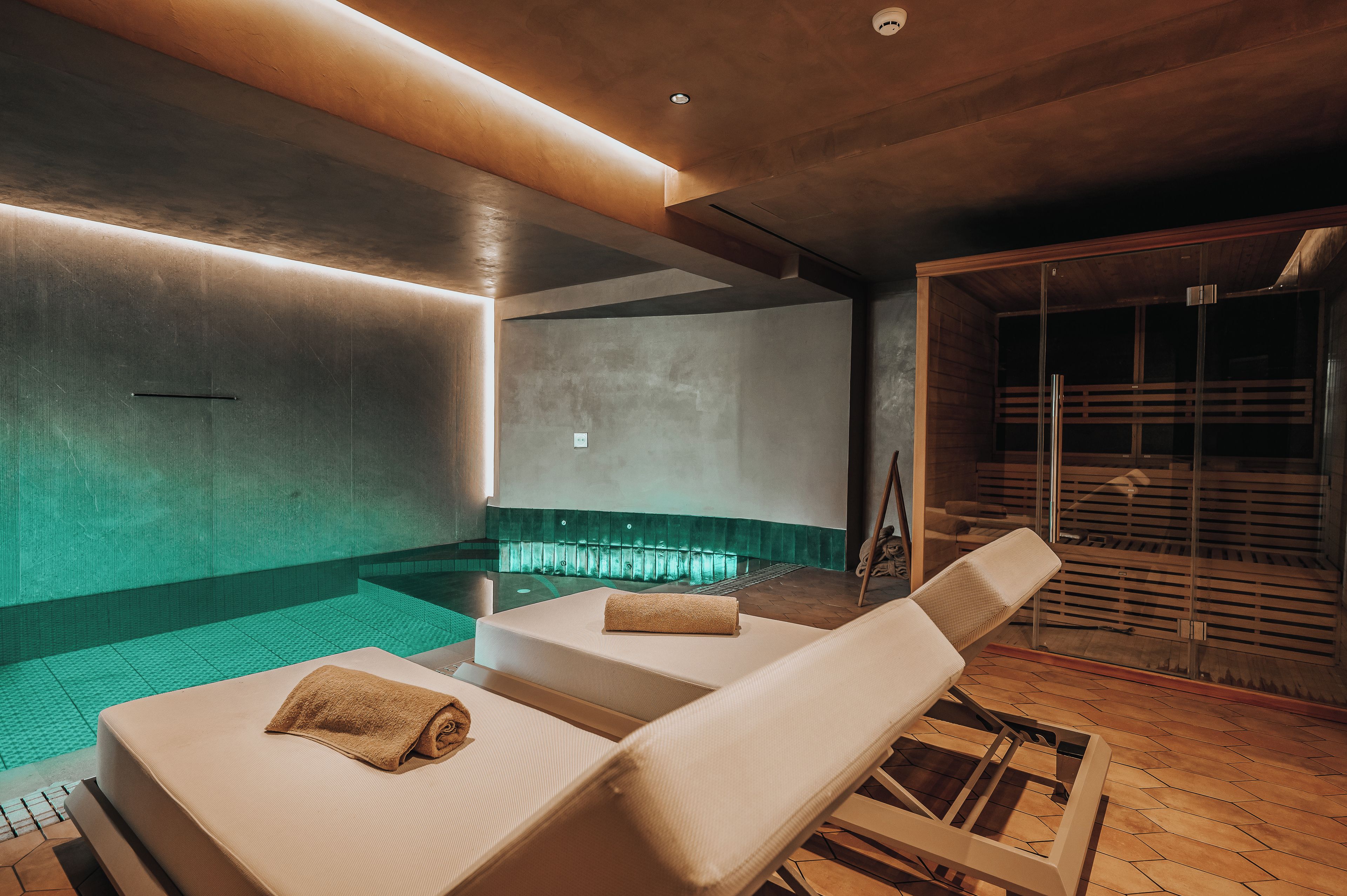 A spa area with two lounge chairs, a small pool, and a sauna.