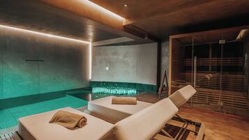 A spa area with two lounge chairs, a small pool, and a sauna.