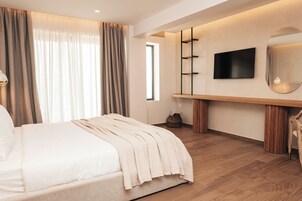 A modern bedroom with a bed, a TV mounted on the wall, and a large window with curtains.