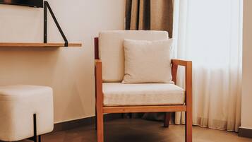 A wooden chair with a cushion, a small ottoman, and a flat-screen TV mounted on the wall.
