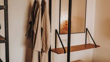 A room with a wooden bunk bed, a small stool, and a mirror on the wall.