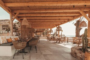 An outdoor patio with wooden furniture, woven chairs, and a thatched ceiling. - Sagredo Boutique Hotel And Spa (Kos)