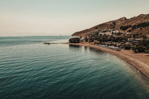 Eine Küstenstadt mit Strand, Gebäuden und hügeliger Landschaft im Hintergrund.