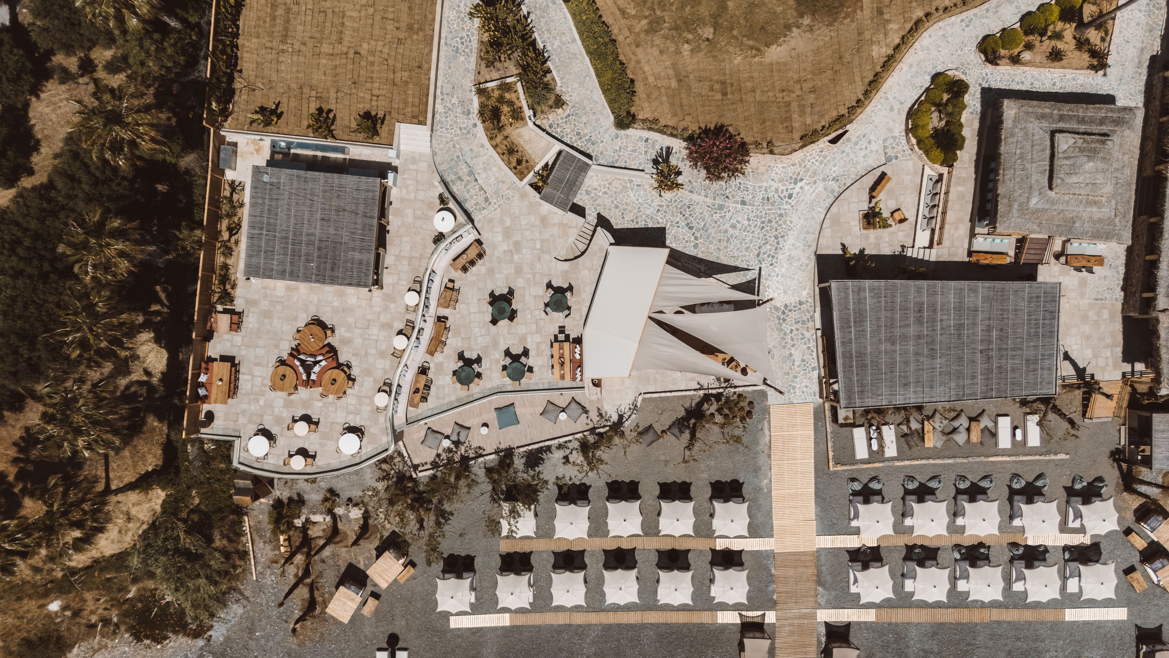 An aerial view of a hotel with a central courtyard, multiple dining areas, and a parking lot.