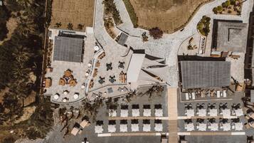 An aerial view of a hotel with a central courtyard, multiple dining areas, and a parking lot.