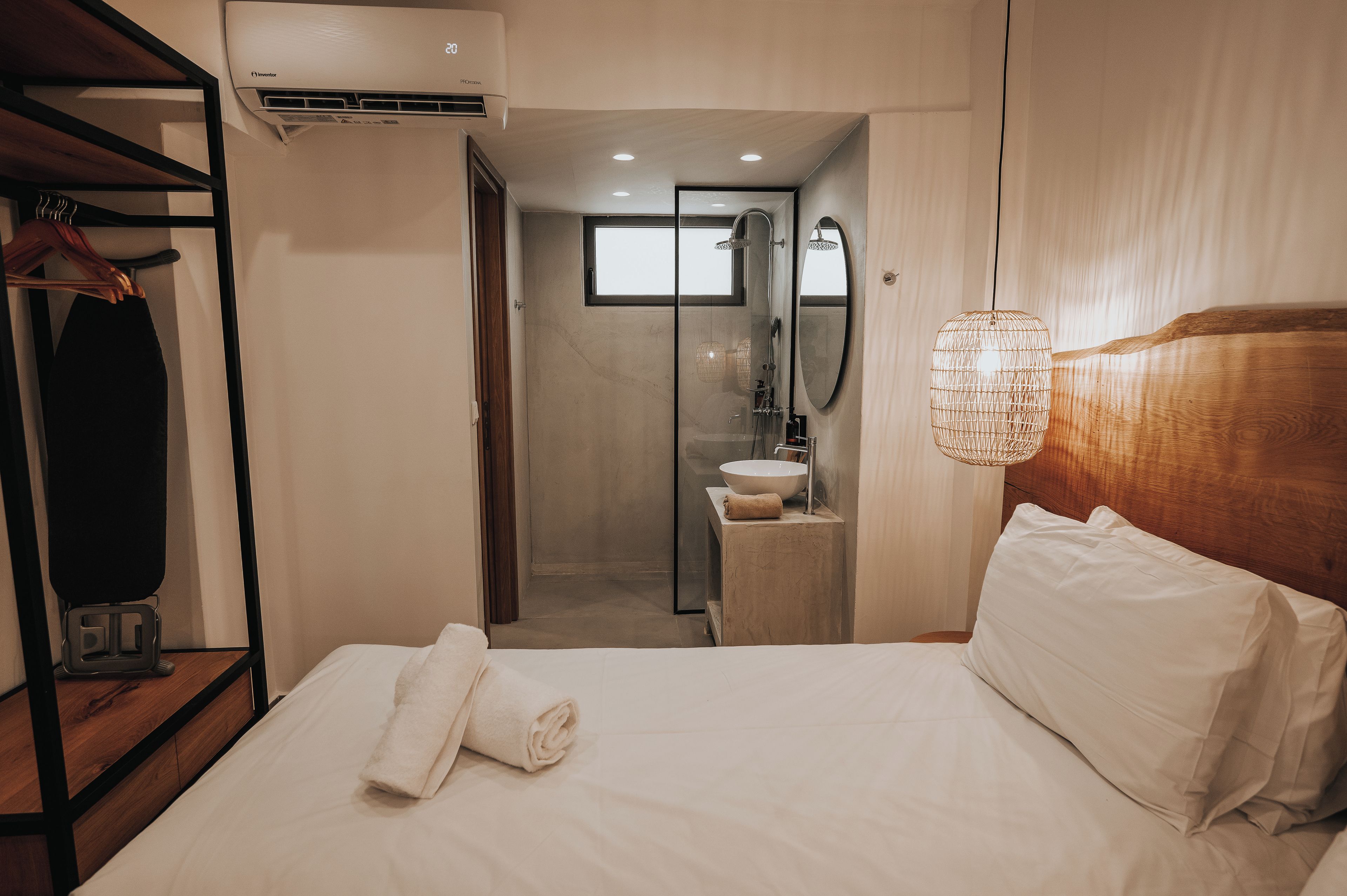 Ein Hotelzimmer mit Bett, Handtuch, Dusche und einem hölzernen Kopfteil.